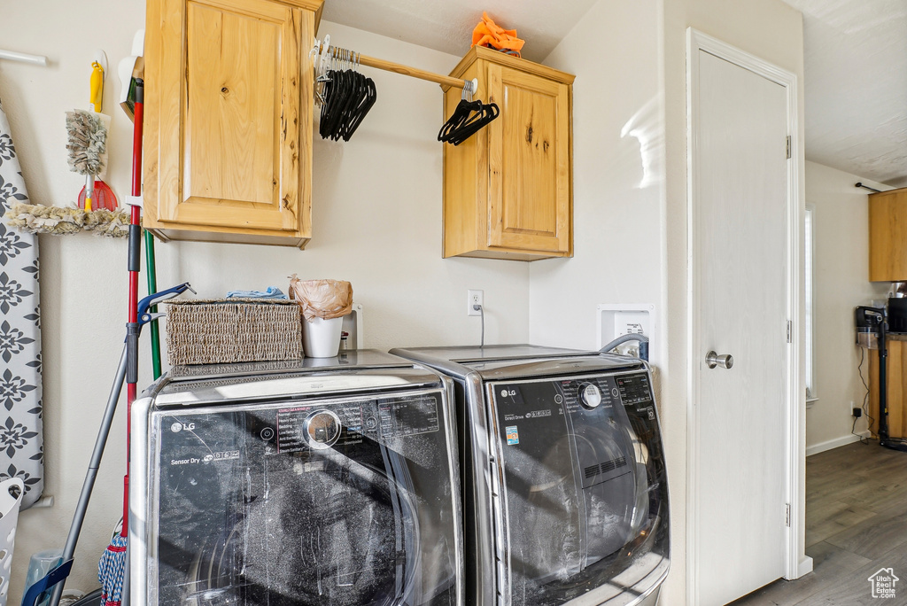 Laundry area with cabinet space, independent washer and dryer, and wood finished floors
