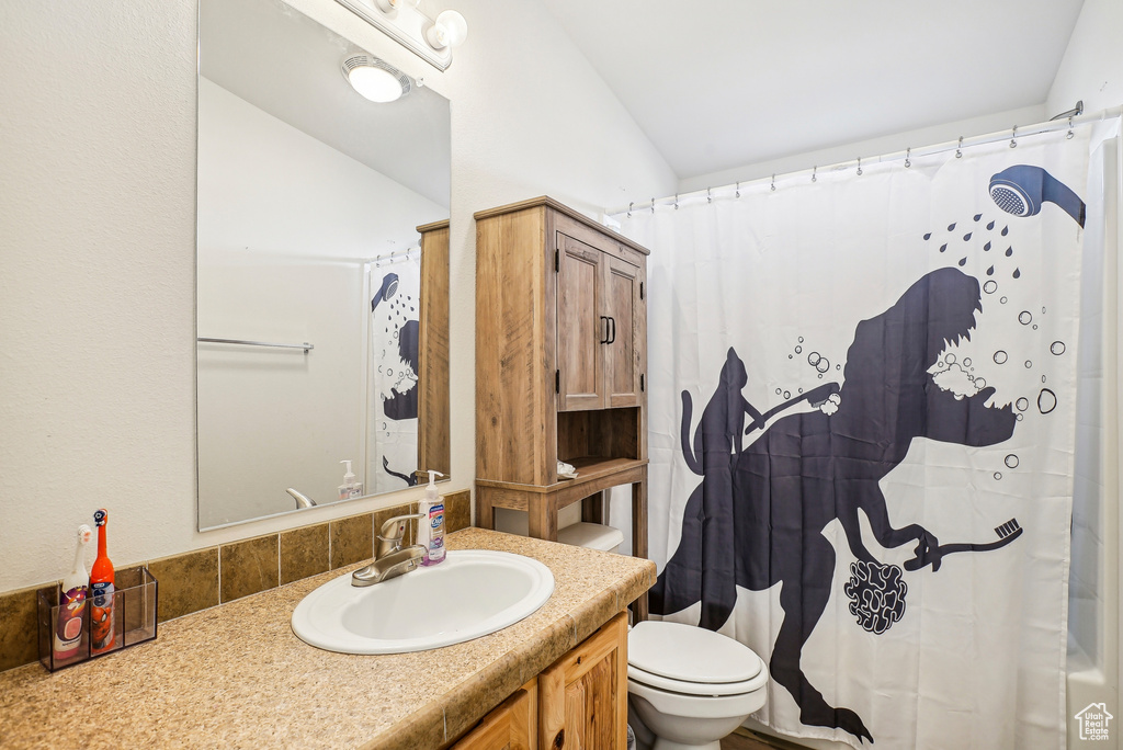 Full bathroom featuring vanity, toilet, curtained shower, and lofted ceiling