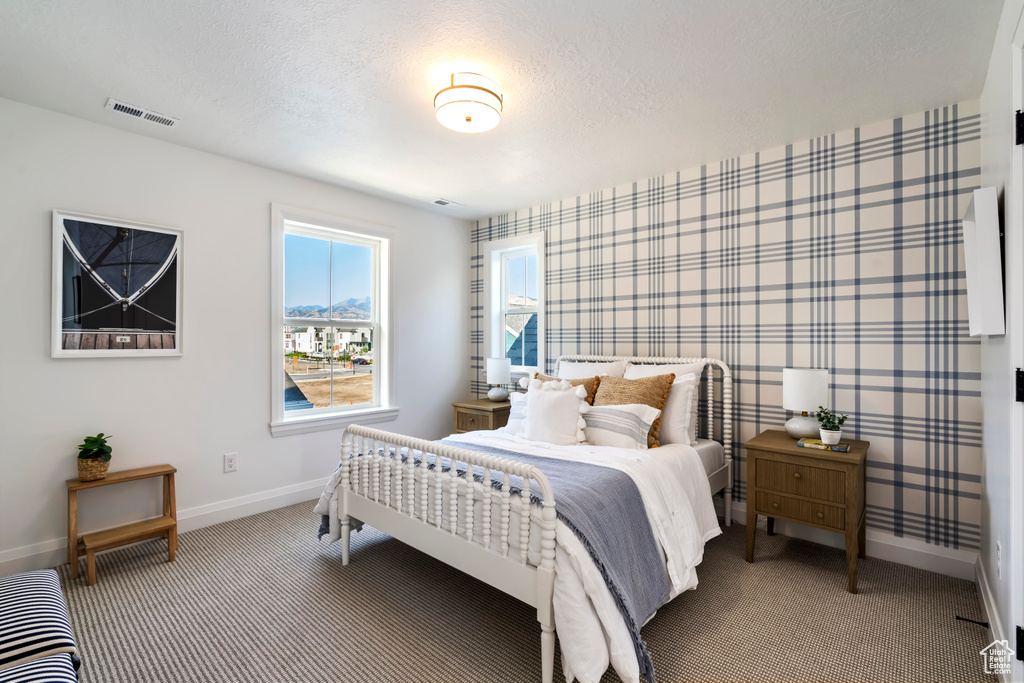 Bedroom featuring visible vents, baseboards, wallpapered walls, a textured ceiling, and carpet