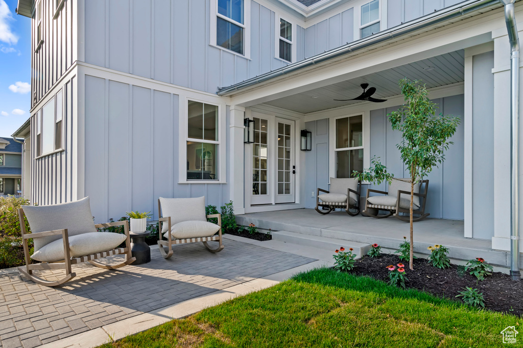 Property entrance featuring board and batten siding, a patio, a ceiling fan, and covered porch
