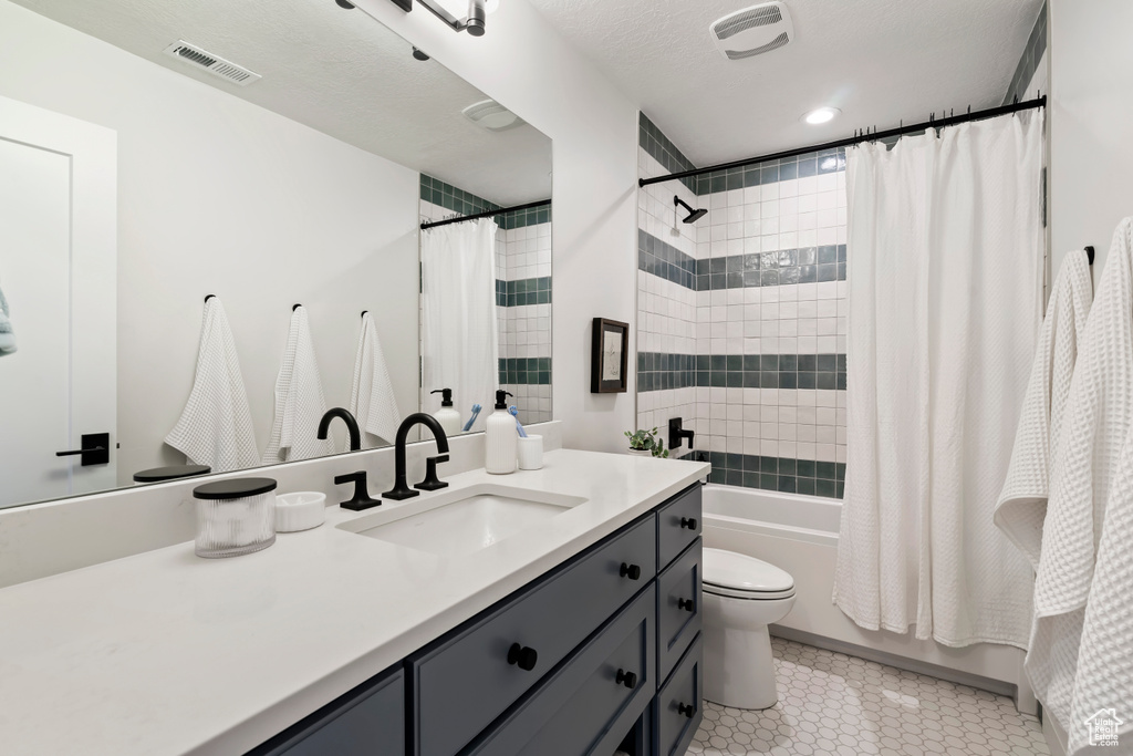 Full bathroom with shower / bath combination with curtain, visible vents, vanity, tile patterned floors, and toilet