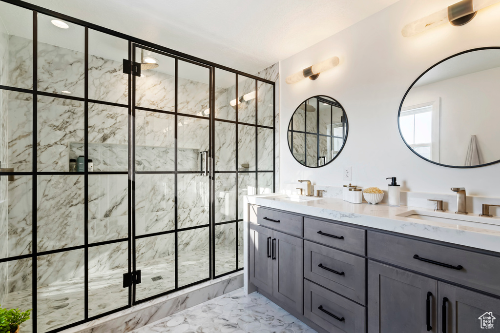 Full bath featuring a sink, a shower stall, double vanity, and marble finish floor