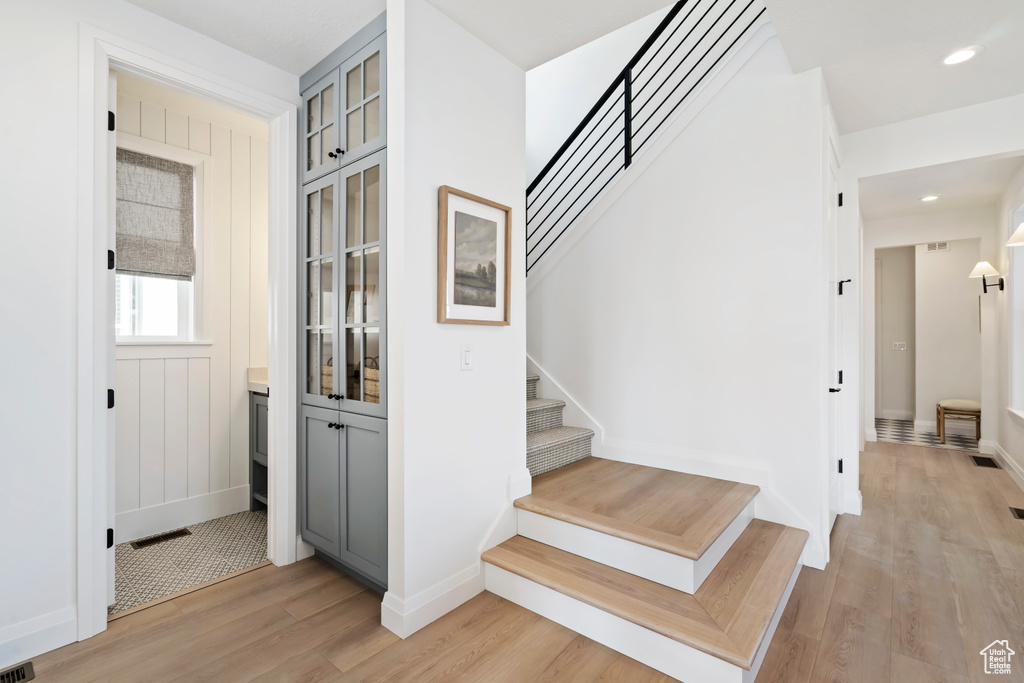 Staircase featuring baseboards, recessed lighting, wood finished floors, and visible vents
