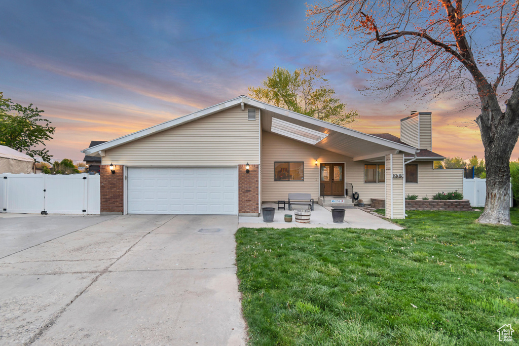 Mid-century inspired home featuring fence, a front lawn, a gate, a chimney, and concrete driveway