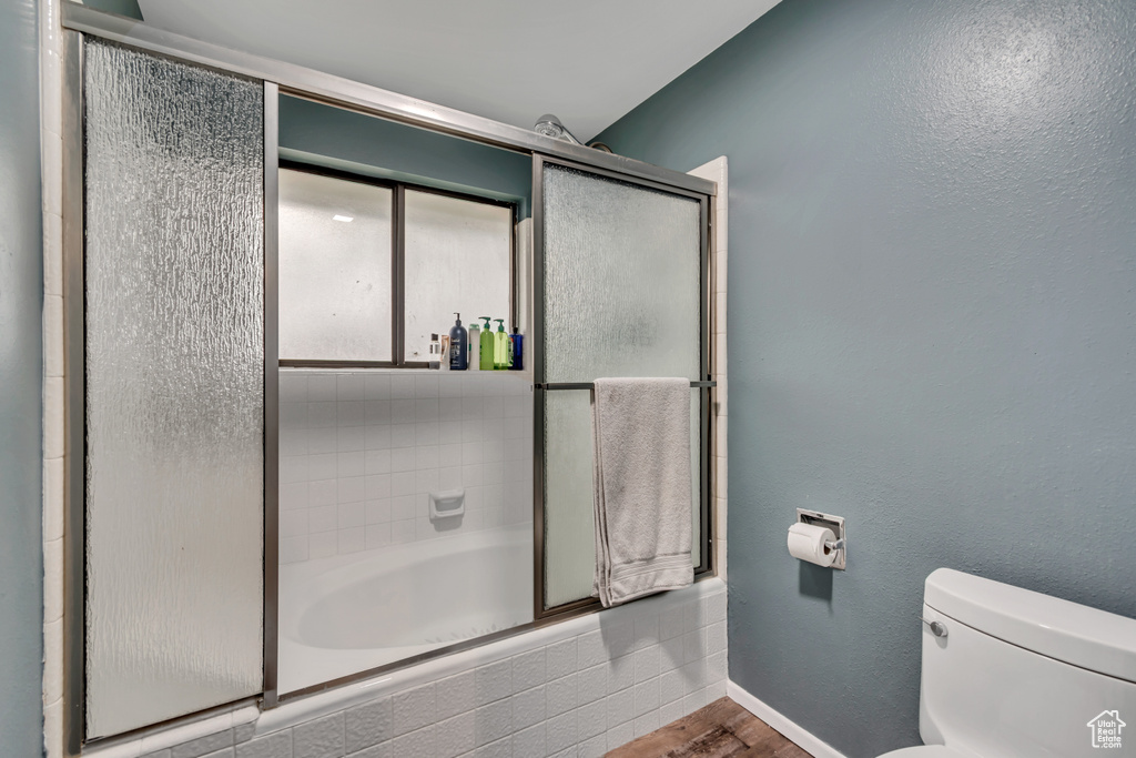 Bathroom featuring baseboards, toilet, and wood finished floors