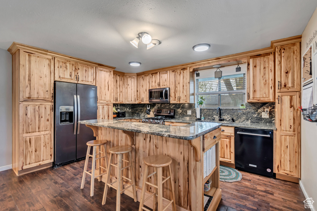 Kitchen featuring light brown cabinetry, tasteful backsplash, and stainless steel appliances