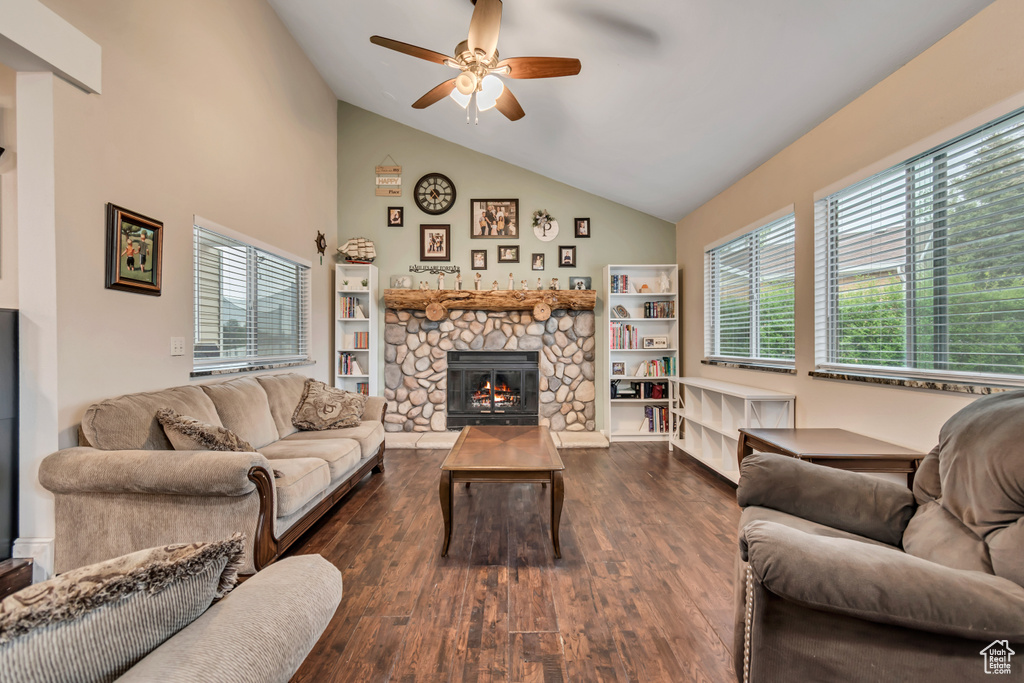 Living room featuring ceiling fan, a stone fireplace, wood finished floors, and plenty of natural light
