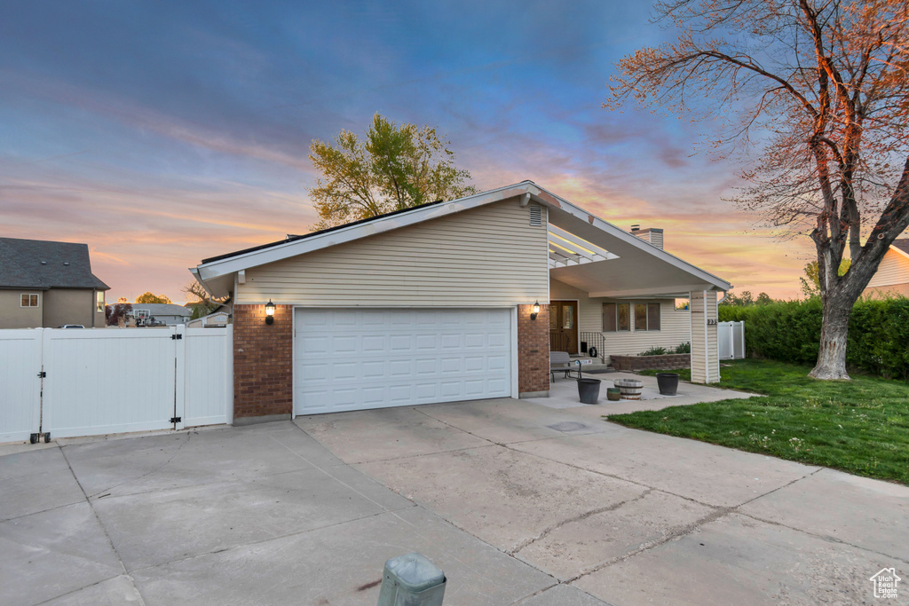 Mid-century home featuring brick siding, driveway, fence, and a gate