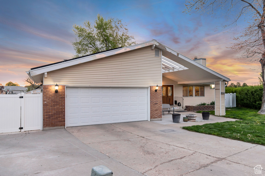 Mid-century home with fence, concrete driveway, and brick siding