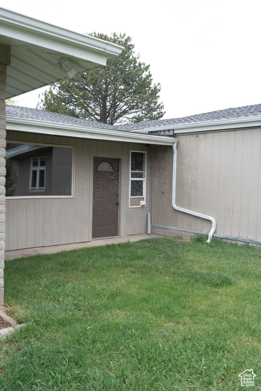 Entrance to property with a lawn and roof with shingles
