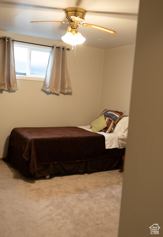 Carpeted bedroom with a ceiling fan
