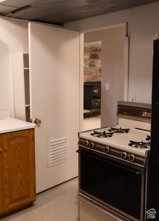 Kitchen with light countertops, brown cabinets, and gas stove