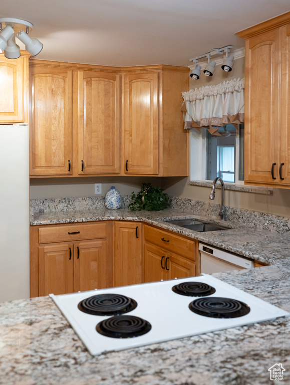 Kitchen with white appliances, light stone countertops, and a sink