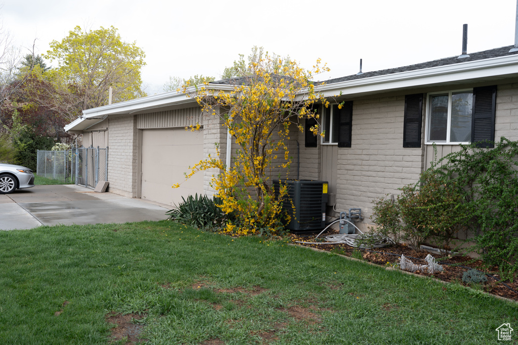 View of home\\\'s exterior featuring a garage, concrete driveway, a yard, and brick siding