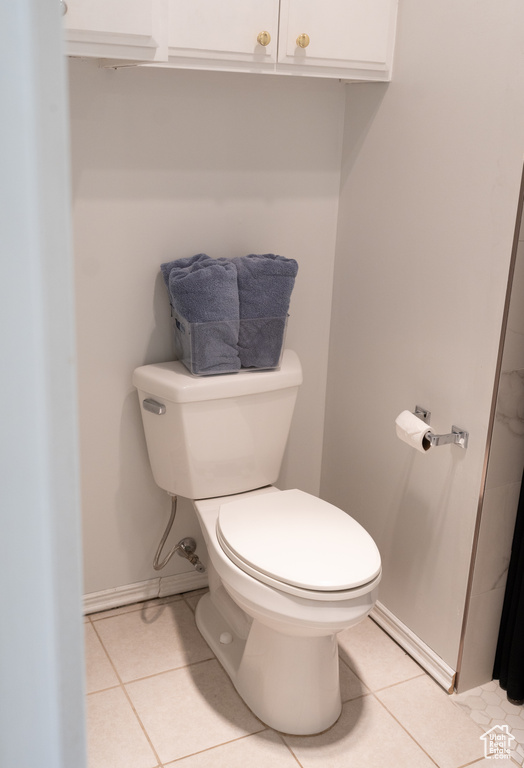 Bathroom with toilet, tile patterned floors, and baseboards