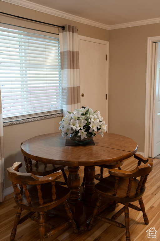 Dining space featuring baseboards, ornamental molding, and light wood-style flooring