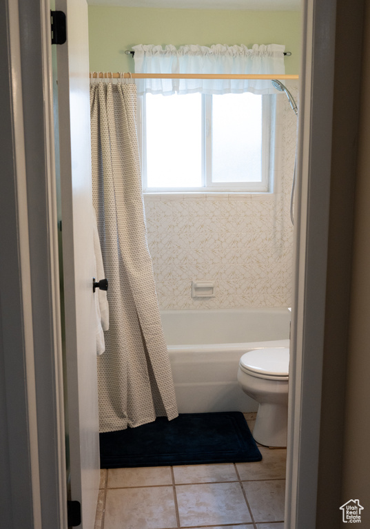 Bathroom with tile patterned floors, toilet, and shower / tub combo with curtain