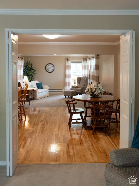 Dining area featuring crown molding, baseboards, baseboard heating, and wood finished floors