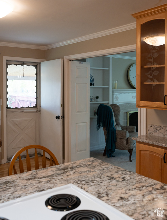 Kitchen with crown molding, carpet, light stone counters, and glass insert cabinets