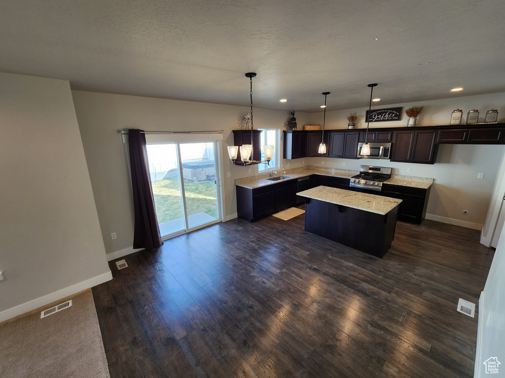 Kitchen with a center island, baseboards, appliances with stainless steel finishes, and dark wood finished floors