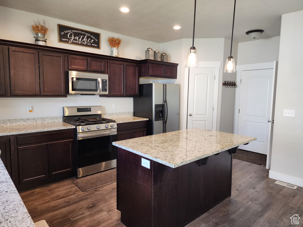 Kitchen featuring stainless steel appliances, dark wood-style flooring, dark brown cabinets, recessed lighting, and a center island