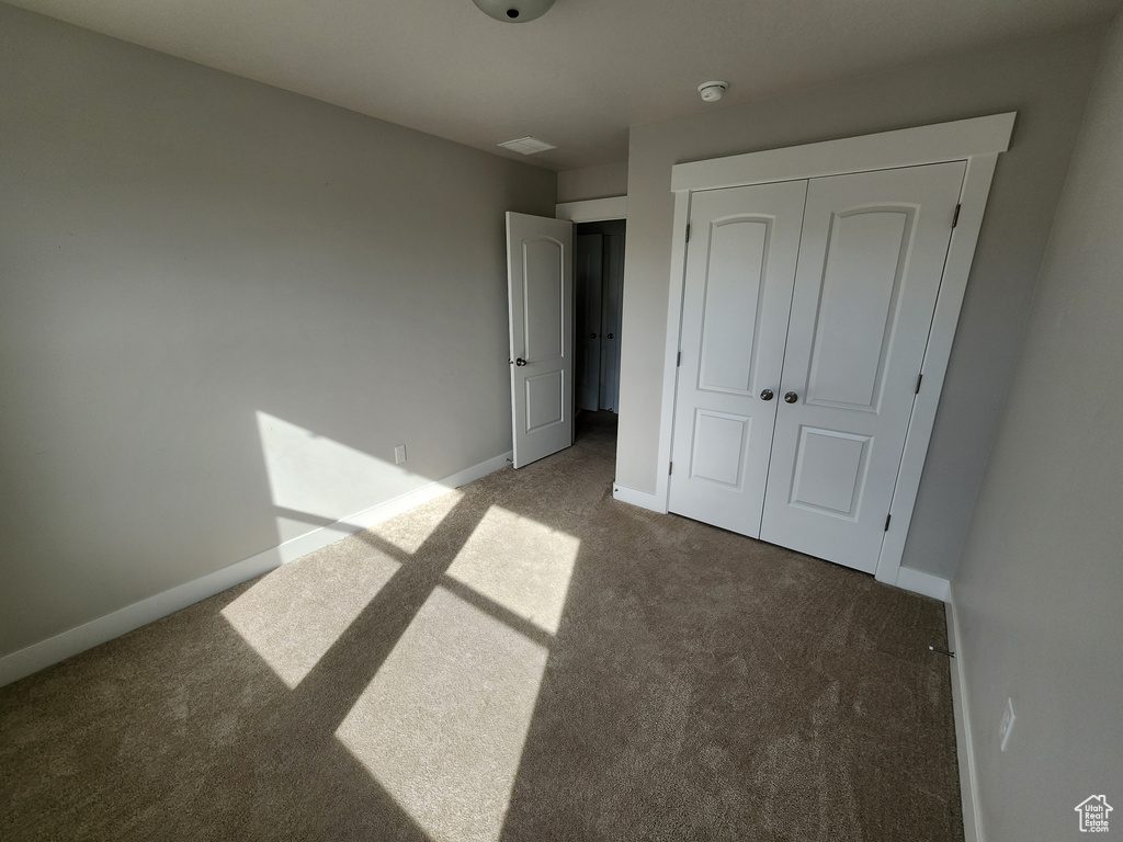 Unfurnished bedroom featuring carpet floors, baseboards, and a closet