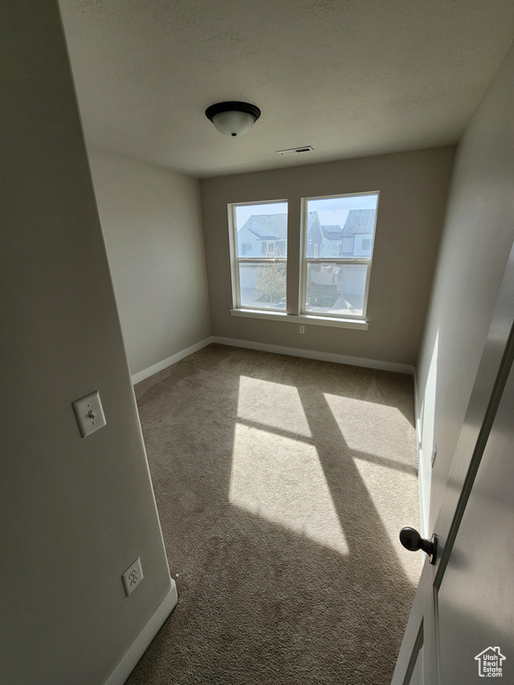 Carpeted spare room featuring baseboards and visible vents