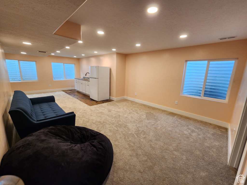 Living area featuring baseboards, light carpet, and recessed lighting