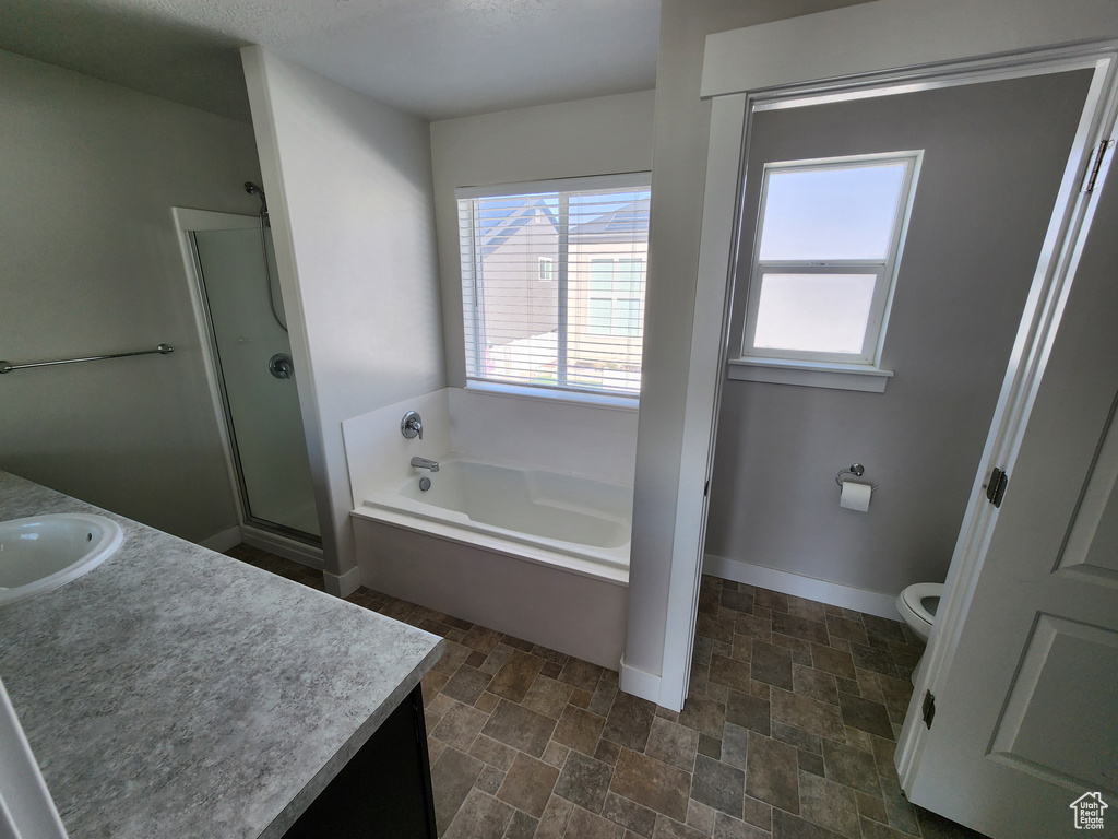 Bathroom with vanity, toilet, stone finish floor, a shower stall, and a bath
