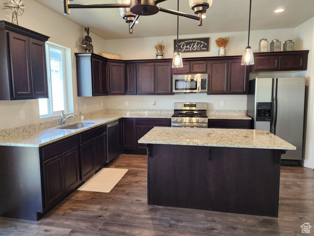 Kitchen featuring appliances with stainless steel finishes, a sink, a kitchen island, dark brown cabinets, and a ceiling fan