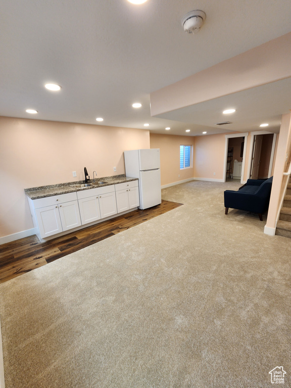 Finished basement featuring carpet, baseboards, freestanding refrigerator, and indoor wet bar