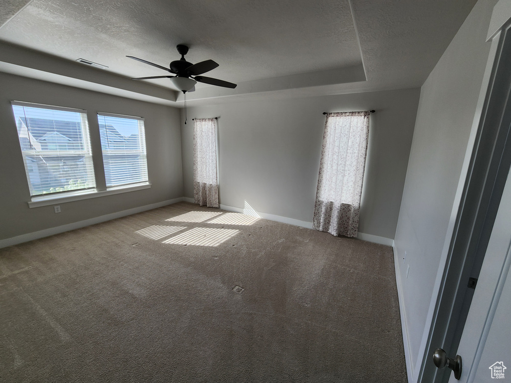 Spare room featuring visible vents, baseboards, a raised ceiling, a textured ceiling, and carpet