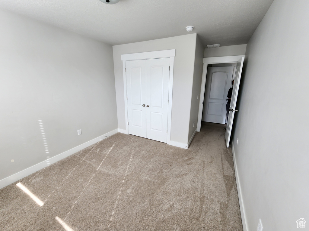 Unfurnished bedroom featuring carpet flooring, baseboards, and a closet