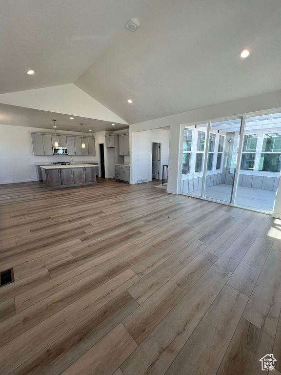 Unfurnished living room featuring visible vents, vaulted ceiling, recessed lighting, and light wood finished floors