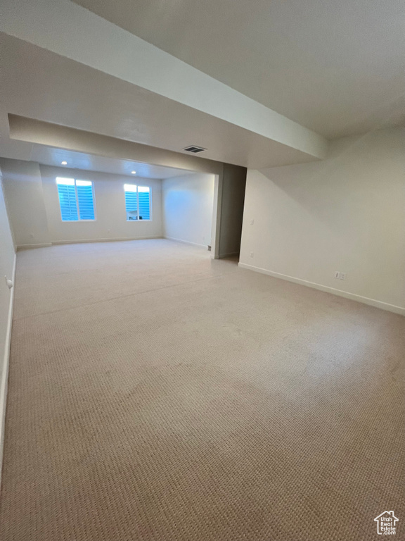Below grade area featuring light colored carpet, baseboards, and visible vents