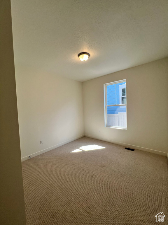 Carpeted empty room featuring a textured ceiling, baseboards, and visible vents