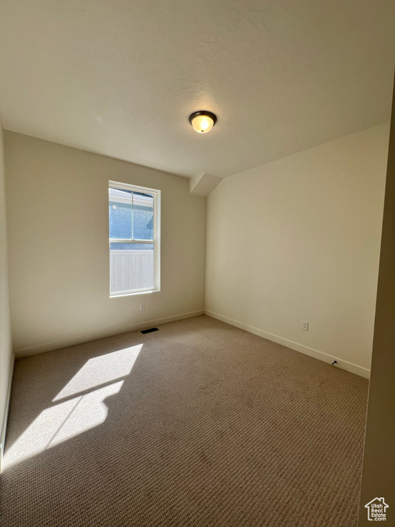 Carpeted spare room featuring visible vents and baseboards