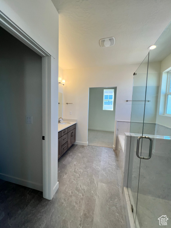 Bathroom with vanity, a wealth of natural light, a bath, and a stall shower