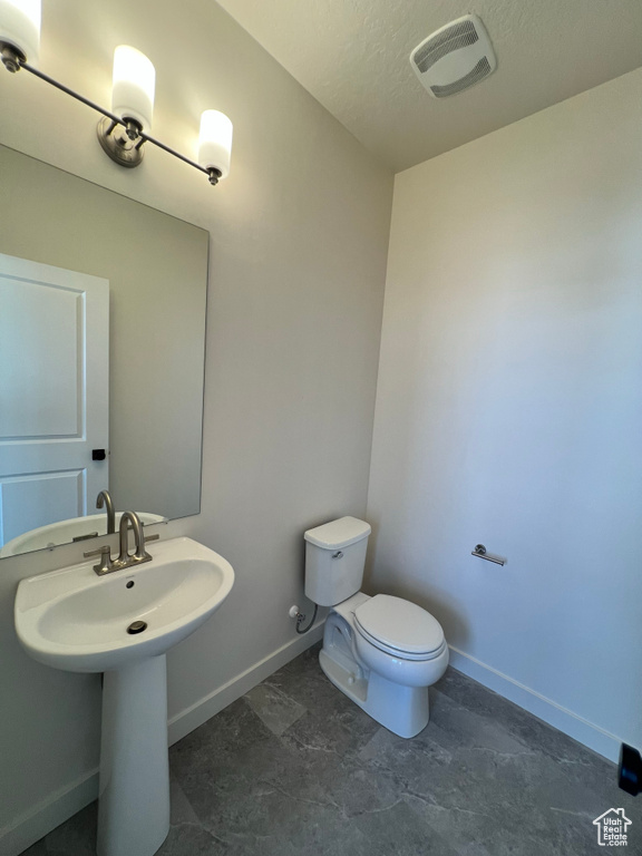 Bathroom with visible vents, a textured ceiling, baseboards, and toilet