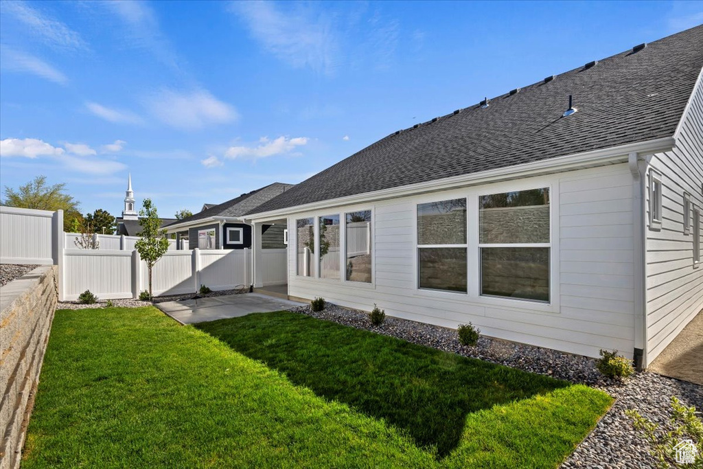 Back of house with fence, a yard, a patio area, and roof with shingles