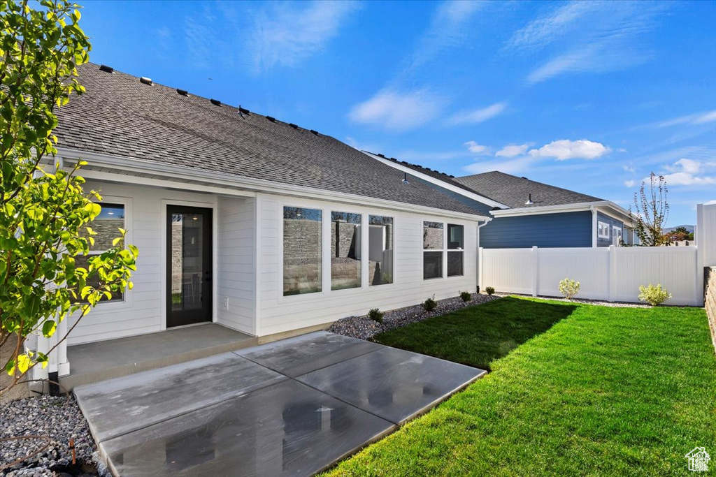 Rear view of house featuring a yard, a patio, fence, and roof with shingles