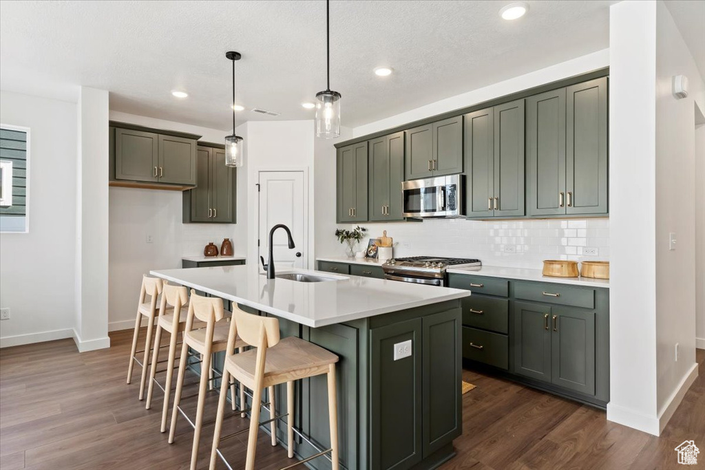 Kitchen with a sink, baseboards, stainless steel appliances, and dark wood finished floors