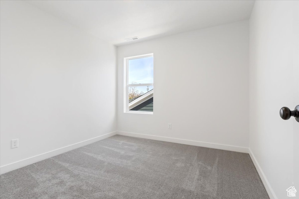 Empty room with baseboards, visible vents, and carpet