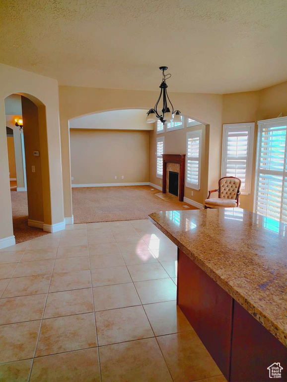Interior space featuring arched walkways, a textured ceiling, light tile patterned floors, and a wealth of natural light