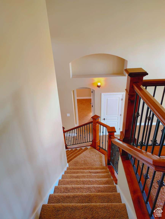 Stairs with baseboards and arched walkways