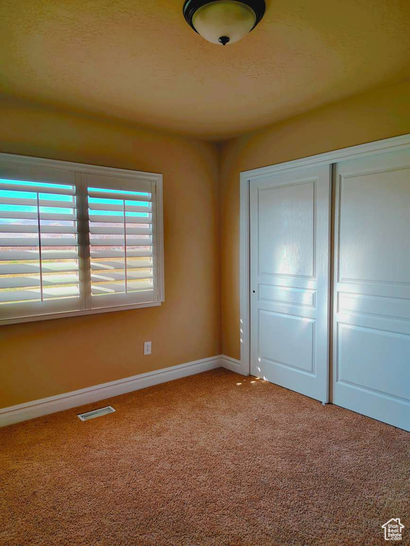 Unfurnished bedroom featuring a closet, carpet, baseboards, and visible vents