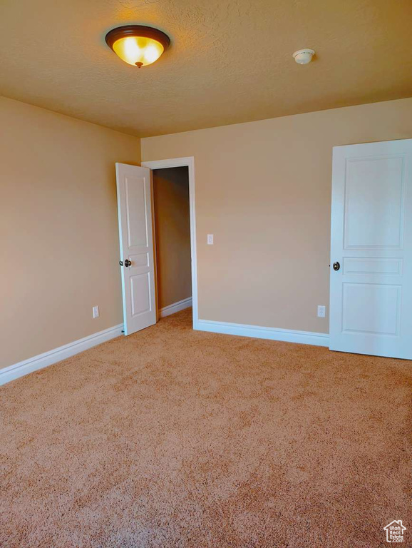 Spare room with baseboards and light carpet