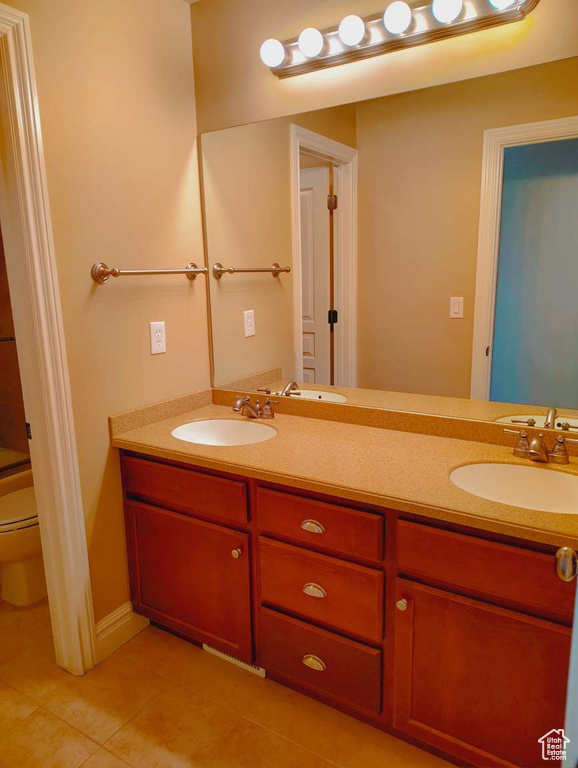 Bathroom with a sink, tile patterned floors, toilet, and double vanity