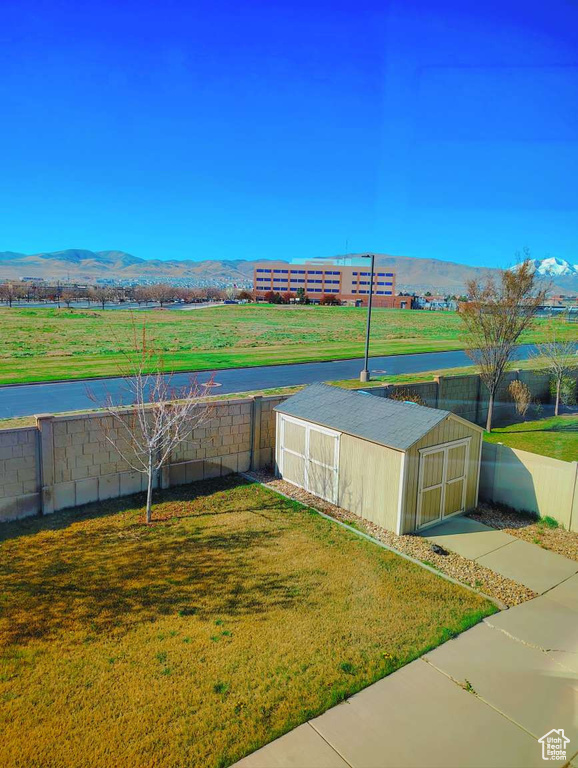Exterior space with a lawn, an outdoor structure, a mountain view, and a fenced backyard