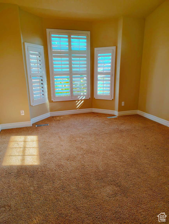 Spare room featuring carpet flooring, baseboards, and visible vents